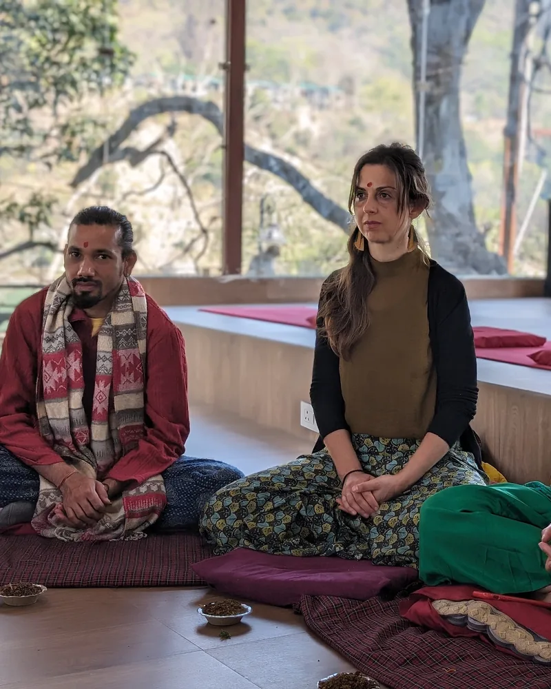 Yoga teacher guiding a small-group meditation class in Rishikesh