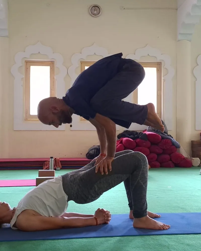 Yoga teacher demonstrating supported partner practice in class